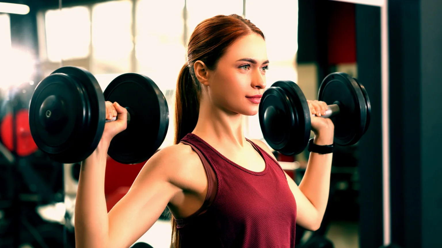 photo - Woman performs the shoulder press with a pair of dumbbells