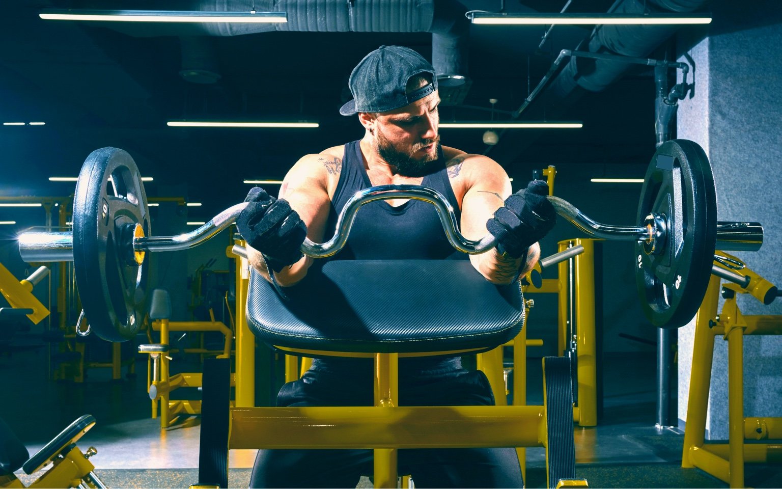 Man uses a preacher curl bench at the gym