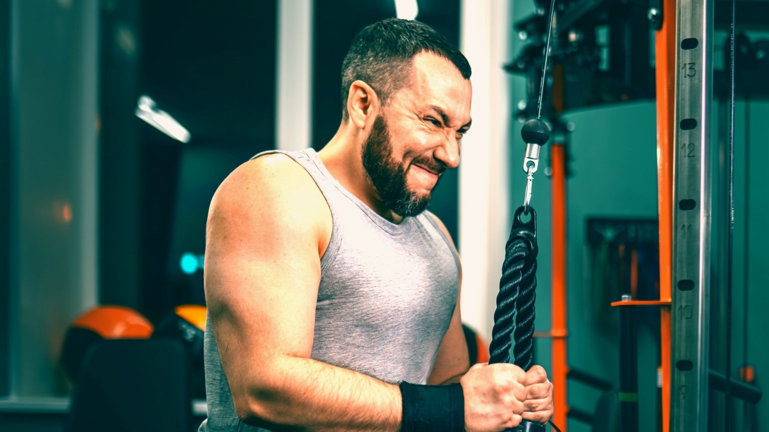 Man performs a tricep pulldown. This exercise is part of the PHAT workout routine.