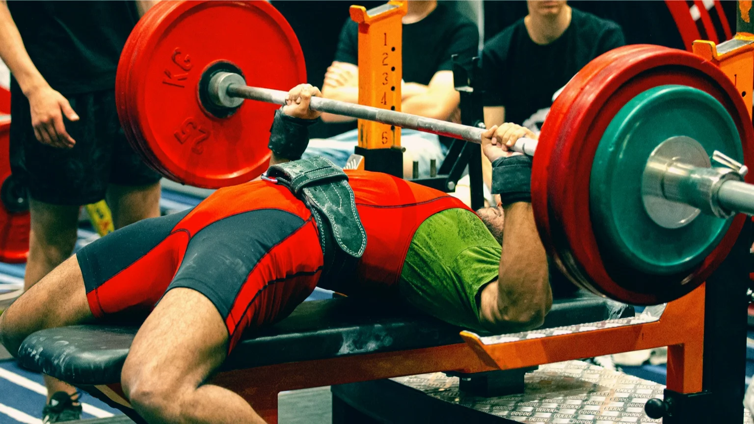 photo - Man performs the bench press at a powerlifting competition.